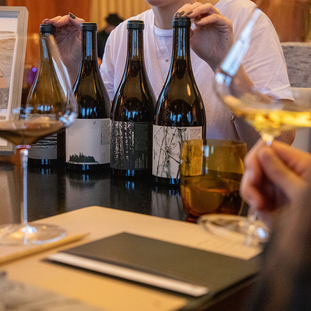 Estate Host explaining details of 4 wine bottles to tasters Estate Host explaining details of 4 wine bottles to tasters